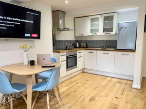 a kitchen with a table with chairs and a laptop on it at Forbury Apartment, 3 guests, Free Parking & Wifi, close to Uni, Hospital & Town Centre in Reading