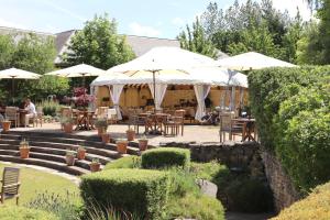 un patio con mesas y sombrillas en un jardín en The Vineyard Hotel & Spa en Newbury