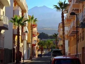 a city street with palm trees and a mountain at Casa Cecilia in Playa de San Juan