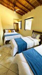 um quarto com 3 camas com lençóis azuis e brancos em Pousada Antares de Paraty em Paraty