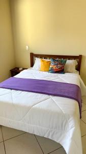 a bedroom with a large bed with a purple blanket at Pousada Antares de Paraty in Paraty