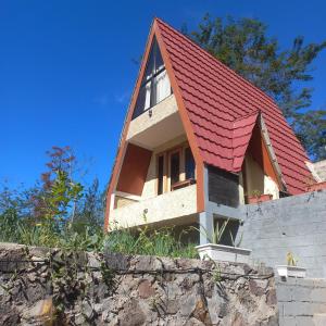ein Haus mit rotem Dach über einer Wand in der Unterkunft Agora Home in Wonosobo
