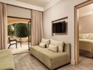 ein Schlafzimmer mit einem Bett, einem Sofa und einem TV in der Unterkunft Atlantica Aphrodite Hills Hotel in Kouklia