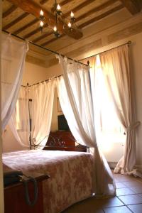 ベヴァーニャにあるレジデンツァ ポルタ グエルファのベッドルーム(白いカーテン付きのベッド1台付)