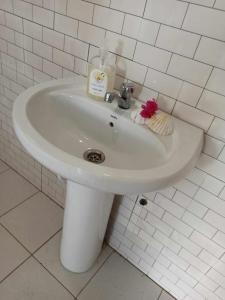 a white sink in a white tiled bathroom at Bosofet Beach and Creek Lodge in Sanyang