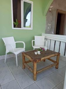 a coffee table and two white chairs on a porch at Bosofet Beach and Creek Lodge in Sanyang