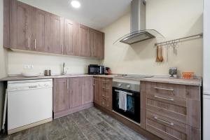 cocina con armarios de madera y lavavajillas blanco en Casa Lluma, en Aldover