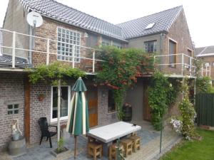 een patio met een tafel en een parasol voor een huis bij Boskanthuisje in Kluisbergen