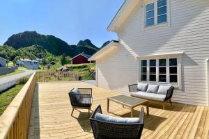 a wooden deck with chairs and a table and a house at NorSpan Lodge - Lofoten with Seaview in Stamsund