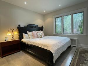 a bedroom with a large bed and two windows at Private Suite in Forest Hill with full kitchen and parking in Toronto