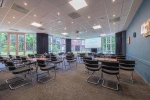 a conference room with tables and chairs and a screen at Amrâth Berghotel Amersfoort, BW Signature Collection in Amersfoort