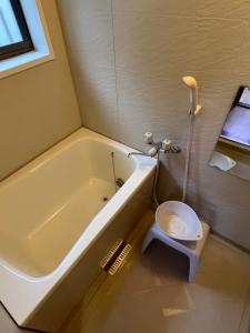 ein Badezimmer mit einer weißen Badewanne und einem WC in der Unterkunft Sepia Court Inn セピアコートイン in Urayasu