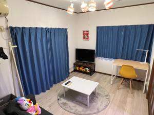 ein Wohnzimmer mit blauen Vorhängen und einem Tisch in der Unterkunft Sepia Court Inn セピアコートイン in Urayasu
