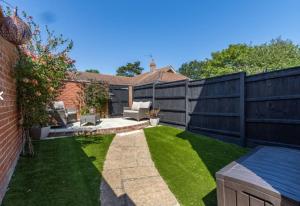 een achtertuin met een zwart hek en gras bij 1 Albert Terrace - Southwold in Reydon
