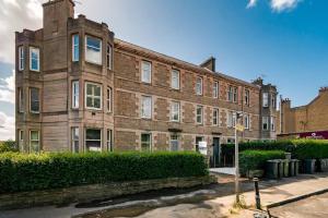 a large brick building with bushes in front of it at Modern 3BHK near Edinburgh zoo in Edinburgh