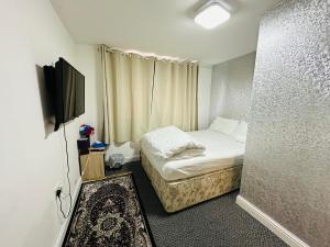 UNIQUE PRIVATE ROOMS في بولتون: غرفة صغيرة بها سرير وتلفزيون بشاشة مسطحة