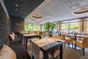 a restaurant with tables and chairs and windows at Amrâth Berghotel Amersfoort, BW Signature Collection in Amersfoort