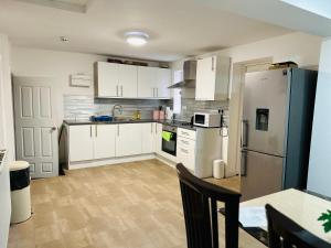 eine Küche mit weißen Schränken und einem Kühlschrank aus Edelstahl in der Unterkunft UNIQUE PRIVATE ROOMS in Bolton
