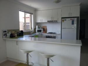 cocina con encimera blanca y nevera blanca en Entire 2BR sunny house @Franklin, Canberra en Canberra