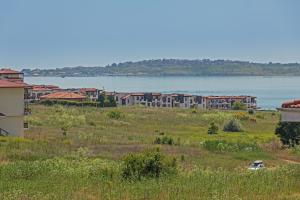 Blick auf ein Feld mit einem Gebäude und das Wasser in der Unterkunft Akladi Family Hotel in Tschernomorez