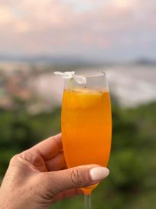 a hand holding a glass of orange juice at Pousada PARAÍSO 26 in Imbituba