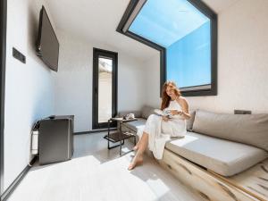 a woman sitting on a couch in a room with a window at Mossa Afkule Kayaköy in Fethiye