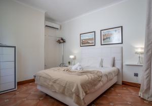 a white bedroom with a large bed and two pictures on the wall at Villa Loureiro Palace With Soccer Field in São Gonçalo