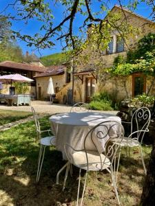 uma mesa e cadeiras em frente a uma casa em Les Paroules - Luxury Dordogne - Holiday Farmhouses. em Saint-Cybranet