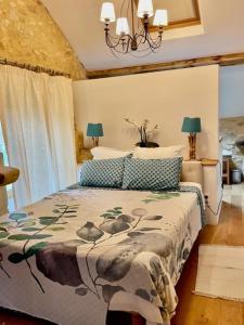 um quarto com uma cama e um lustre em Les Paroules - Luxury Dordogne - Holiday Farmhouses. em Saint-Cybranet