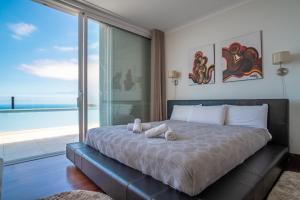 a bedroom with a large bed with a view of the ocean at Villa Loureiro Palace With Soccer Field in São Gonçalo