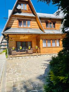 ein Holzhaus mit einer Terrasse davor in der Unterkunft Apartament Władek in Biały Dunajec