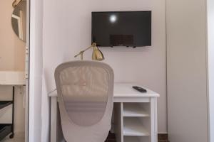 escritorio blanco con silla y TV en la pared en La Bussola, en Las Palmas de Gran Canaria