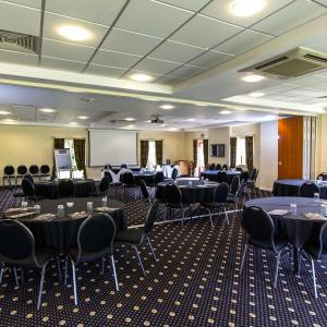 a conference room with tables and chairs and a screen at Padbrook Park Hotel in Cullompton