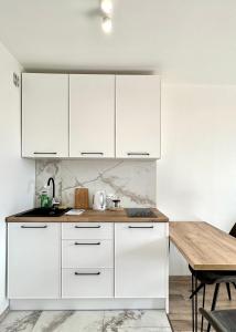 a kitchen with white cabinets and a wooden table at Mirovski Apartment in Warsaw
