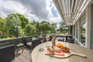 uma mesa com copos de vinho e comida numa varanda em Amrâth Airport Hotel Rotterdam, BW Signature Collection em Roterdão