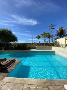 een blauw zwembad met stoelen en palmbomen bij MANDAI Apartamento Cabo Frio in Cabo Frio