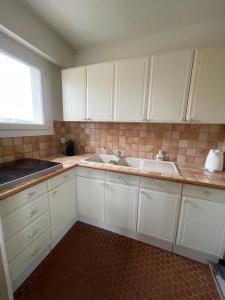 a kitchen with white cabinets and a sink and a window at Logement 4à6 pers à 100m de la mer in Stella-Plage
