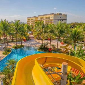 einen Pool in einem Resort mit einer gelben Rutsche in der Unterkunft BARRETOS COUNTRY in Barretos