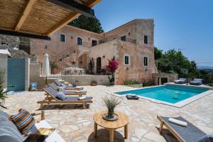 an outdoor patio with a swimming pool and a building at Butterfly, a historical villa with pool & hot tub! in Arménoi