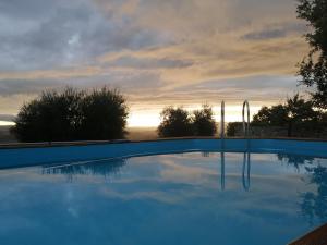 una piscina azul con puesta de sol en el fondo en Vecchio Casale Quercetino, en Montenero