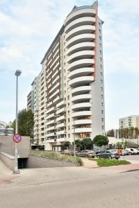 a tall white building in a parking lot at Trzy Żagle - City View Apartments with Balcony by Renters in Gdańsk