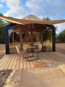 a gazebo with a table and chairs on a wooden deck at La cabane in Beaurepaire