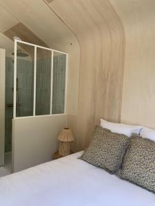 a bedroom with a white bed and a mirror at La cabane in Beaurepaire