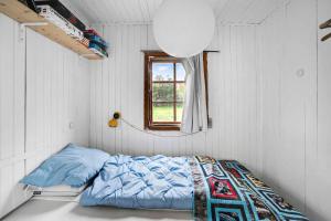 een bed in een witte kamer met een raam bij Cozy Beach House In Northern Part Of Seeland in Vejby