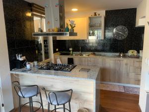 a kitchen with a counter with stools and a stove at Hermosa casa cerca de Aeropuerto in Quito