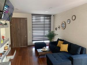 een woonkamer met een blauwe bank en een tafel bij Hermosa casa cerca de Aeropuerto in Quito
