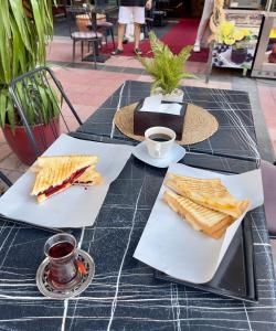 a table with two plates of sandwiches and a cup of coffee at Central Izmir Delight: Cozy Alsancak Apartment in Konak