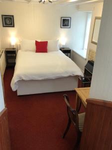 a bedroom with a white bed with a red pillow at Ardvane Bed & Breakfast in Pitlochry
