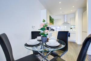 uma mesa de vidro com cadeiras pretas e uma cozinha em Flat In Greenwich O2 With Parking em Londres