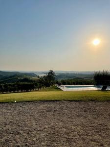 a pool in a field with the sun in the sky at Ca' Colomba in San Damiano dʼAsti